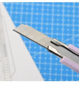 Nahaufnahme der Klinge des Bastelmessers mit rosa Griff zeigt präzise Details auf blauer Matte.