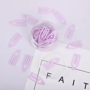 Detailaufnahme von kreativen lila Plastik Büroklammern um einen transparenten Behälter.