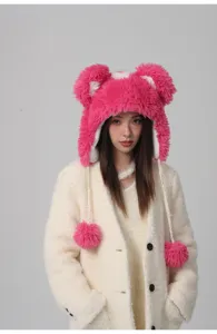Junge Frau mit einer leuchtend rosa flauschigen Bärenohrenmütze und weißen Pompons.