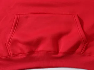 Detailed close-up view of the red hoodie kangaroo pocket and ribbed hem craftsmanship.