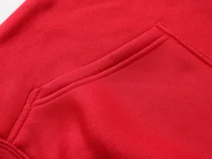 Close-up detail shot of the front pocket and fine stitching on a casual red hoodie.