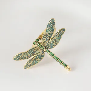 Detalle en primer plano del elegante servilletero de libélula verde y dorada para mesa.