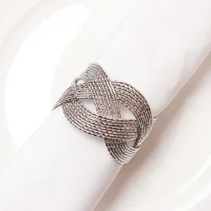 Gros plan d'un rond de serviette en métal tissé argenté sur serviette blanche, détail déco.