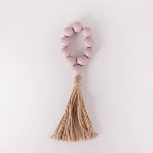 Primer plano detallado del servilletero de cuentas de madera rosa con borla de yute.