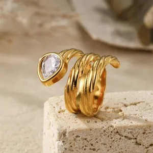 Gedetailleerde close-up van een vergulde ring met meerdere windingen en peervormige steen.