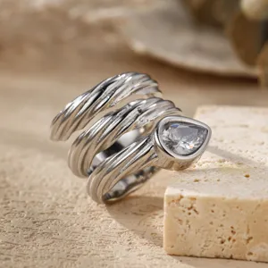 Gedetailleerd shot van meerlagige wikkelring met peervormige steen, zilveren design.