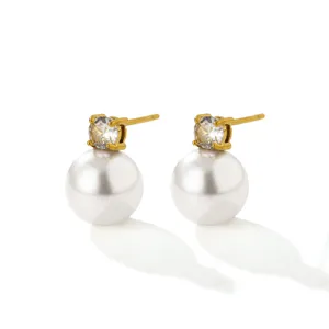 Close-up detail shot of elegant gold plated cubic zirconia and white pearl stud earrings.