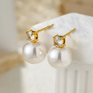 Close-up of elegant gold-plated stud earrings featuring sparkling cubic zirconia and white pearls.