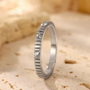 Detailopname van de metalen ring met tandwielstructuur en sprankelende gezette stenen.