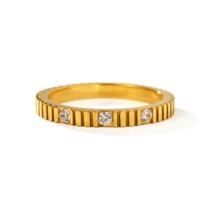 Gedetailleerde close-up van 18K vergulde roestvrijstalen ring met tandwieltextuur en drie stenen.