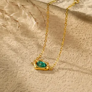 Detailed close-up of a gold-plated irregular necklace featuring a sparkling green cubic zircon.