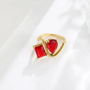 Detail shot of 18k gold plated twin ring with red cubic zirconia geometric hollow design.