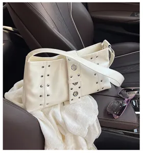 Chic white rivet underarm bag styled on a premium leather car seat with purple sunglasses