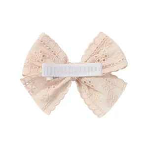 Detail view of the back of a beige lace bow hair clip with a white ribbon-wrapped clip.