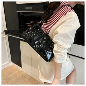 Side view of black punk shoulder bag with studs and eyelets worn by a female model