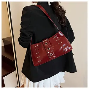 Detailed view of a dark red punk style underarm bag with rivets worn by a model