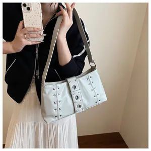 Close-up of stylish silver rivets and grommets on a punk-inspired light grey subaxillary bag