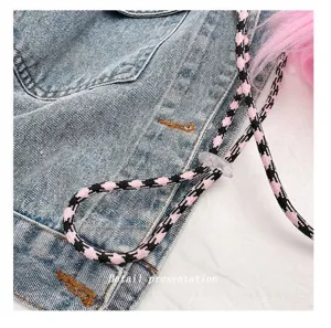 Close-up detail of the stylish pink checkered strap on the denim plush crossbody bag