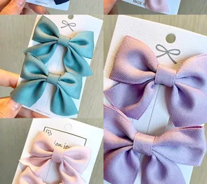 Dettaglio di delicate mollette per capelli a fiocco per bambini in vari colori pastello.