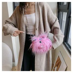 Close-up of a pink plush monster doll crossbody bag worn by a model in a casual setting