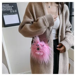 Detail view of a cute pink fuzzy monster crossbody bag worn over a beige cardigan.