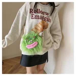 Detailed view of a green hairy monster plush crossbody bag worn by a model in style