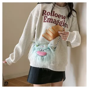 Close-up of a light blue plush monster bag with long fur and braided details.