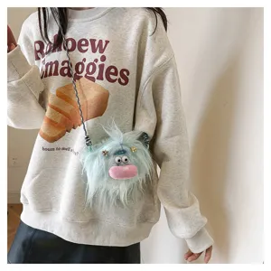 Close-up detail of a cute light blue plush monster doll crossbody bag with long fluffy fur
