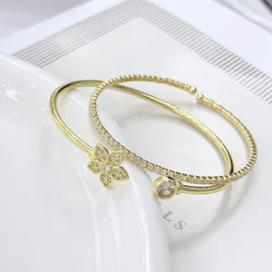 Elegante juego de brazaletes abiertos dorados con motivos florales y de cristales brillantes.