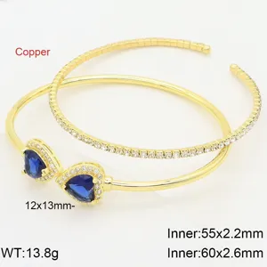 Dettaglio del doppio bracciale dorato in rame con zirconi blu a forma di cuore.