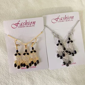 Detailed view of copper cubic zirconia tassel necklace and earrings set with black teardrop stones.
