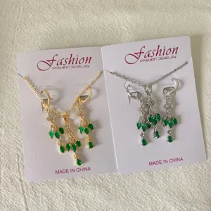 Detailed view of gold and silver tone tassel necklace and earring jewelry set with green stones.