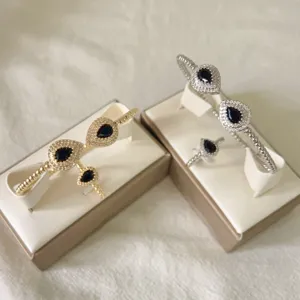 Vista dettagliata del set di bracciali e anelli in zirconi a goccia di lusso oro e argento.