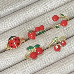Detailweergave van geëmailleerde fruit- en insectenringen met lieveheersbeestje.