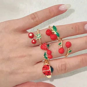 Close-up van kleurrijke emaille aardbei en kers ringen, zoete stijl vinger sieraden.