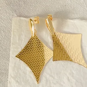 Exquisite Detailaufnahme von goldenen geometrischen Ohrringen mit Retro-Struktur.