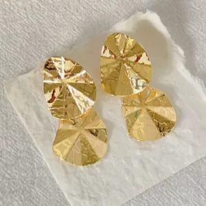 Nahaufnahme von goldenen, gedrehten geometrischen Ohrringen mit strukturierter Optik.