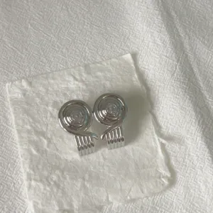 Primo piano di orecchini a spirale vintage argentati con dettagli geometrici dal design unico.