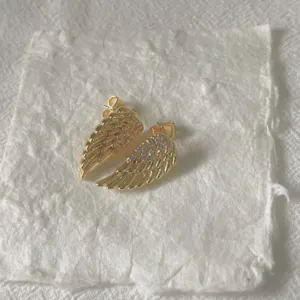 Detailaufnahme von vergoldeten Engelsflügel-Ohrringen mit Zirkonia-Besatz für den Alltag