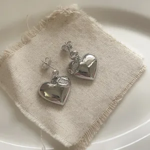 Detail view of silver-tone heart drop earrings with micro-set zircons, elegant luxury style.