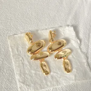 Primo piano dettagliato di eleganti orecchini geometrici irregolari dorati e martellati.