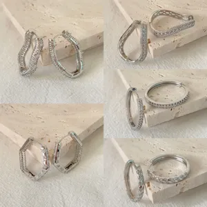 Vista dettagliata di orecchini a cerchio geometrici con pavé di zirconi in varie forme.