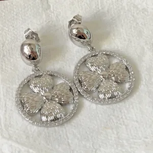 Elegantes pendientes colgantes con diseño de trébol plateado y circonitas brillantes.