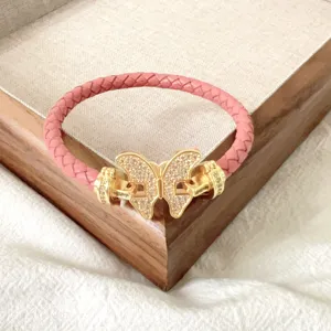 Nahaufnahme des rosa geflochtenen Lederarmbands mit goldenem Schmetterlingsverschluss.