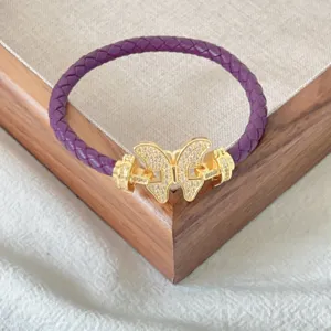 Lila geflochtenes Lederarmband mit goldenem Mikro-Pave-Kristall-Schmetterlingsverschluss.