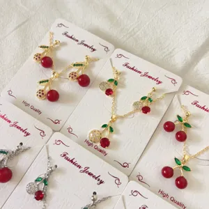 Nahaufnahme der Kirsch-Schmuck-Details mit funkelnden roten Kristallen und grünen Blättern.