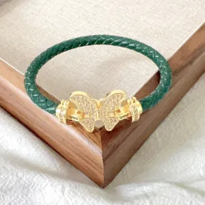 Nahaufnahme eines dunkelgrünen geflochtenen Lederarmbands mit goldenem Schmetterlingsverschluss.