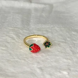 Primo piano del grazioso anello aperto con fragola e fiore, rame dorato con smalto.