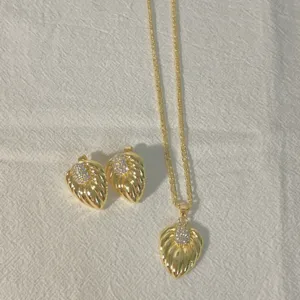 Gedetailleerde opname van vergulde ketting en oorbellen set met fonkelende zirkonia's.