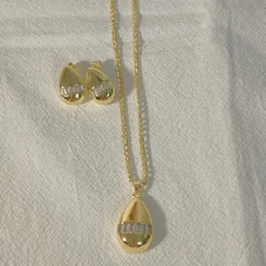 18k gold plated teardrop pendant necklace and matching earrings set with clear baguette zircon stones detail view.
